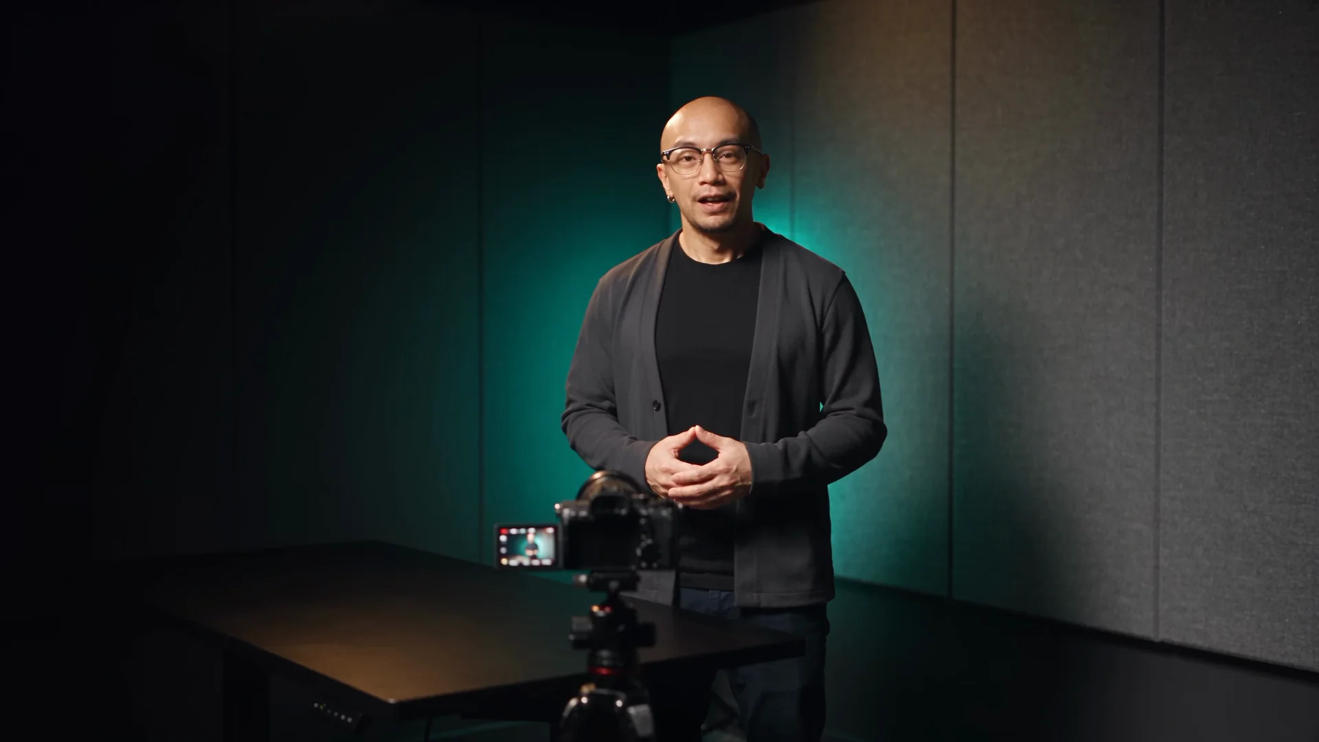 Nelson talking to a camera on a tripod in a moody video studio